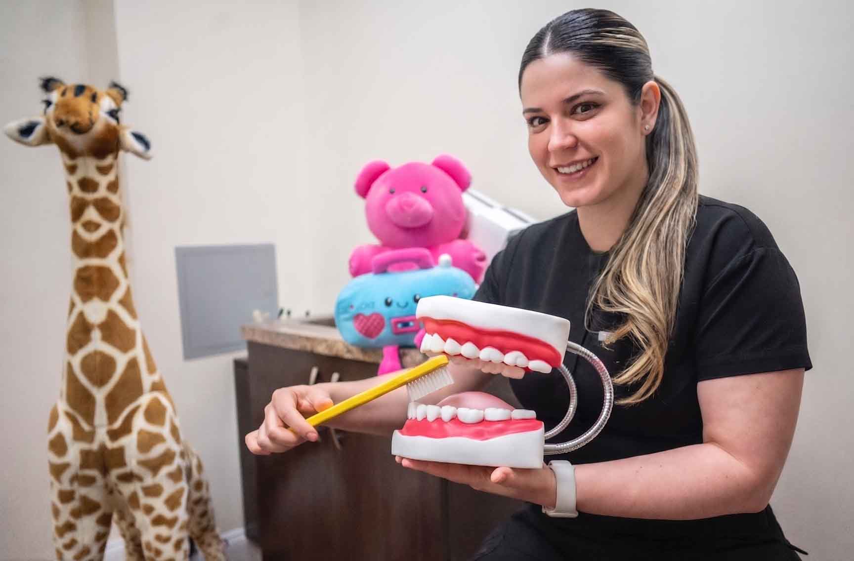 The Aesthetic Dental team in North Bergen, New Jersey offers pediatric dentistry. Here is a photo of a registered dental assistant showing a child patient oral hygiene techniques